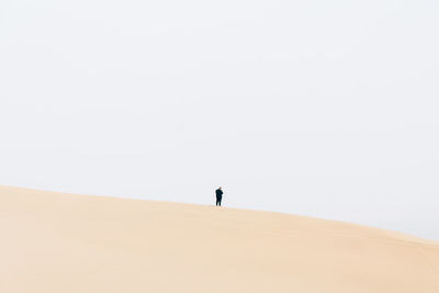 Man standing on desert against clear sky