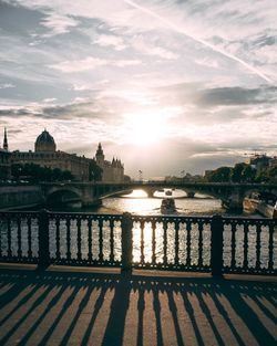 River in city against sky during sunset