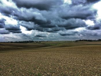 Scenic view of field against storm clouds
