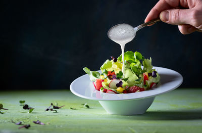 Midsection of person holding fruits in bowl on table