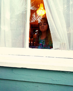 Portrait of girl peeking through window