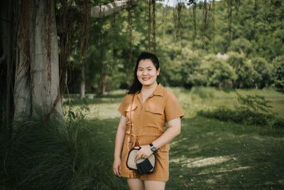 Young woman standing against trees