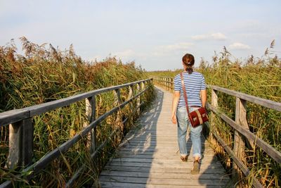 Rear view of woman walking on footbridge