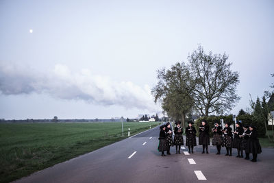 Rear view of people on road against sky