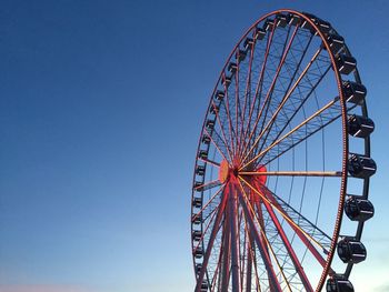 Low angle view of ferris wheel against clear blue sky