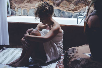 Side view of woman sitting on rock