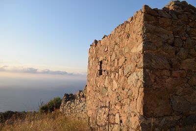 Stone wall by sea against sky