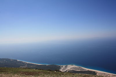 Scenic view of sea and mountains against clear blue sky