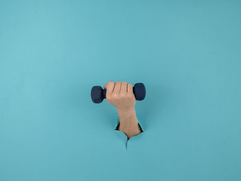 Low angle view of dumbbells on blue background