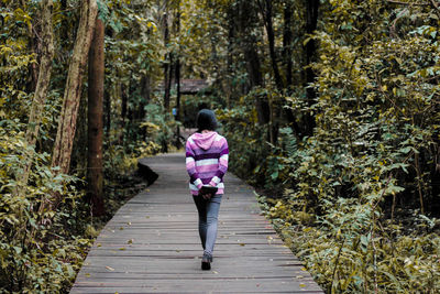 Rear view of woman walking in forest