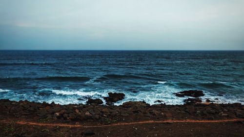 Moody seashore with small waves crashing over pebbles and rocks.