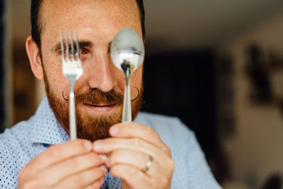 Close up portraits of man with moustache holding fork and spoon