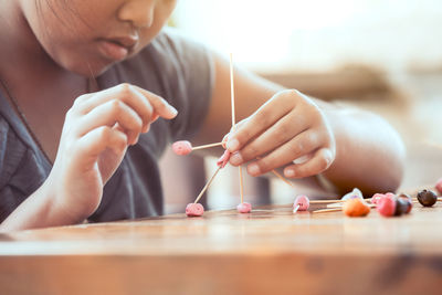 Midsection of girl making molecule model on wooden table in porch