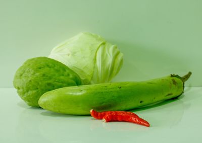 Close-up of green chili pepper on table against white background