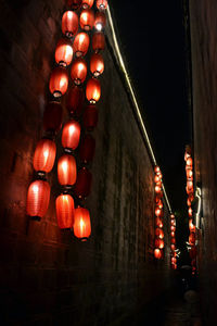 Low angle view of illuminated lanterns hanging by building