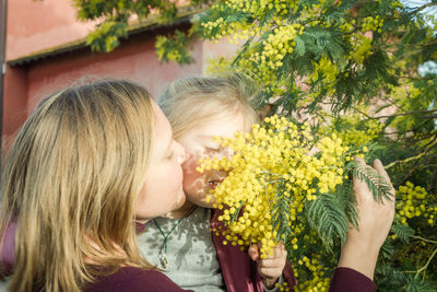 Portrait of a woman with her daughter near a mimosa tree