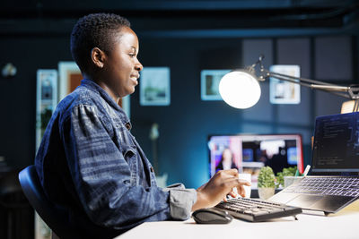 Side view of man using laptop at office