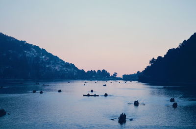 Silhouette people swimming in sea against clear sky