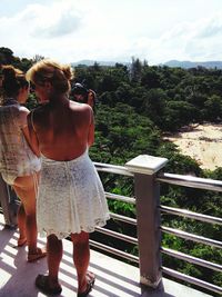 Rear view of woman photographing railing against sky