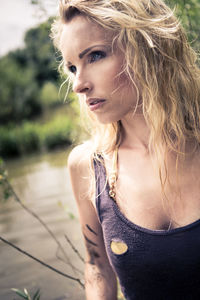 Thoughtful beautiful woman looking away while standing against plants