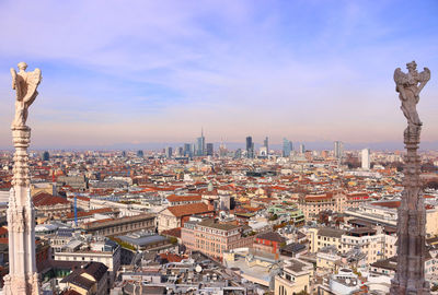 High angle view of city buildings against cloudy sky