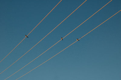 Low angle view of vapor trails against clear blue sky