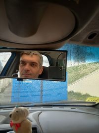 Reflection of man in rear-view mirror of car