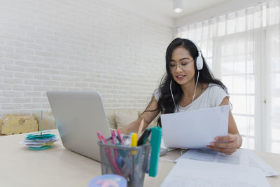 Young woman using mobile phone while sitting on table