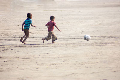 Children playing soccer on beach