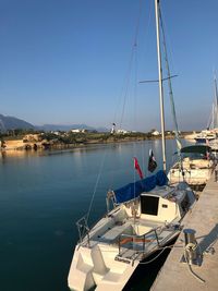 Sailboats moored on sea against clear blue sky