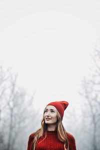 Woman in red hat and sweater walking on foggy mystical morning forest.