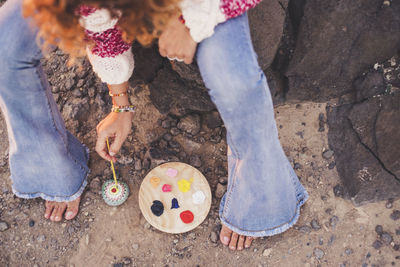 Low section of woman painting stone while sitting on rock