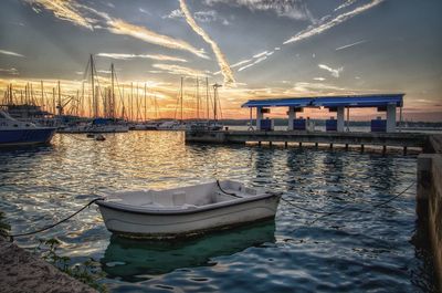 Ship moored at harbor against sky during sunset