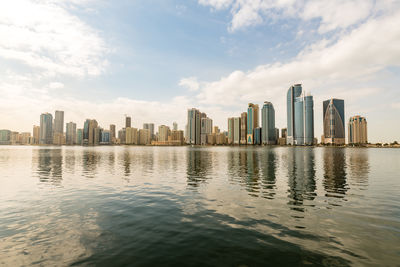 Sea by buildings against sky in city