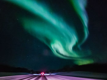 Light trails on road against sky at night