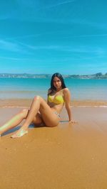 Portrait of seductive young woman sitting on shore at beach