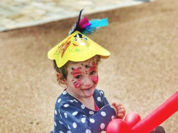 High angle view of girl with face paint and party hat on sand