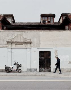 Man walking on street against building in city