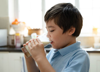 Close-up portrait of boy drinking coffee at home