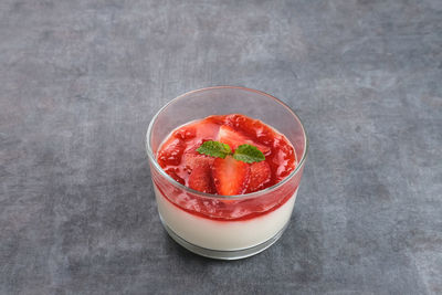 Sweet vanilla silky pudding dessert with strawberry sauce, sliced fresh strawberries and mint