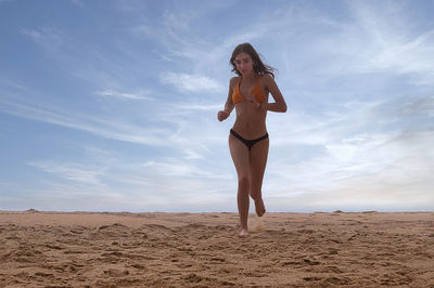 Full length of woman standing on sand at beach against sky