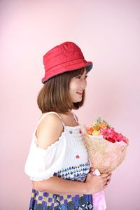 Girl holding ice cream standing against pink background