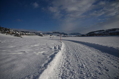 Snow covered road by snowcapped mountain against sky