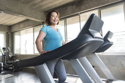 Portrait of woman exercising on treadmill against window