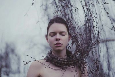 Young woman covered in twigs