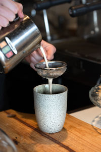 Close-up of hand pouring coffee in cup