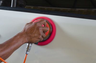 Cropped hand of mechanic polishing car 