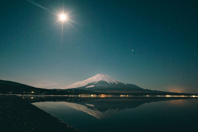 Mount fuji reflecting in lake against sky at night