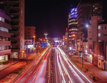 Light trails on road amidst buildings in city at night