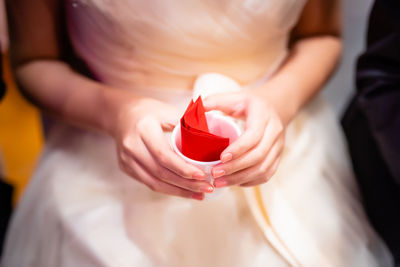 Midsection of a bride holding a cup with red envelope 